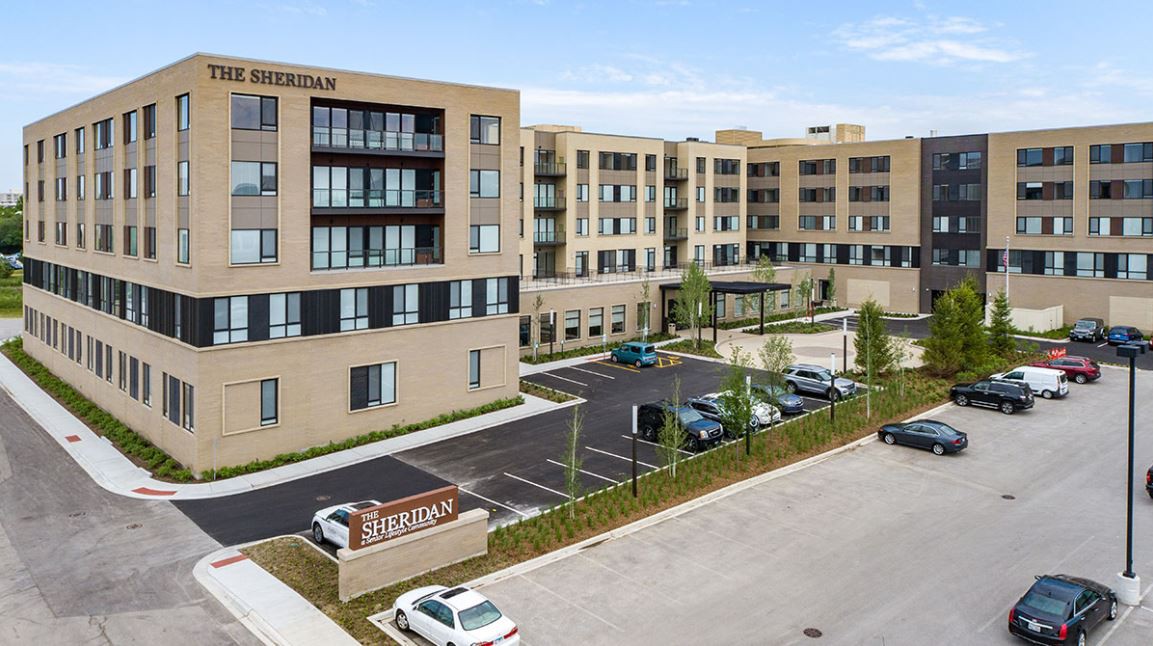 A modern apartment complex with a parking lot and landscaped surroundings.