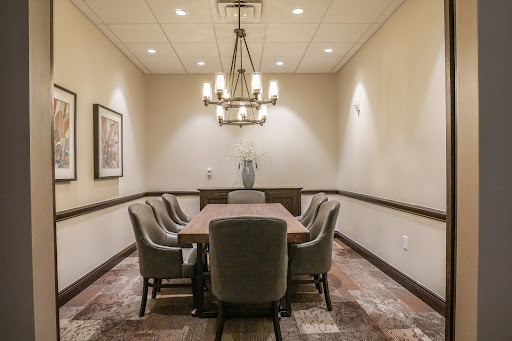 A well-lit meeting room featuring a large conference table and comfortable chairs, suitable for discussions and presentations.