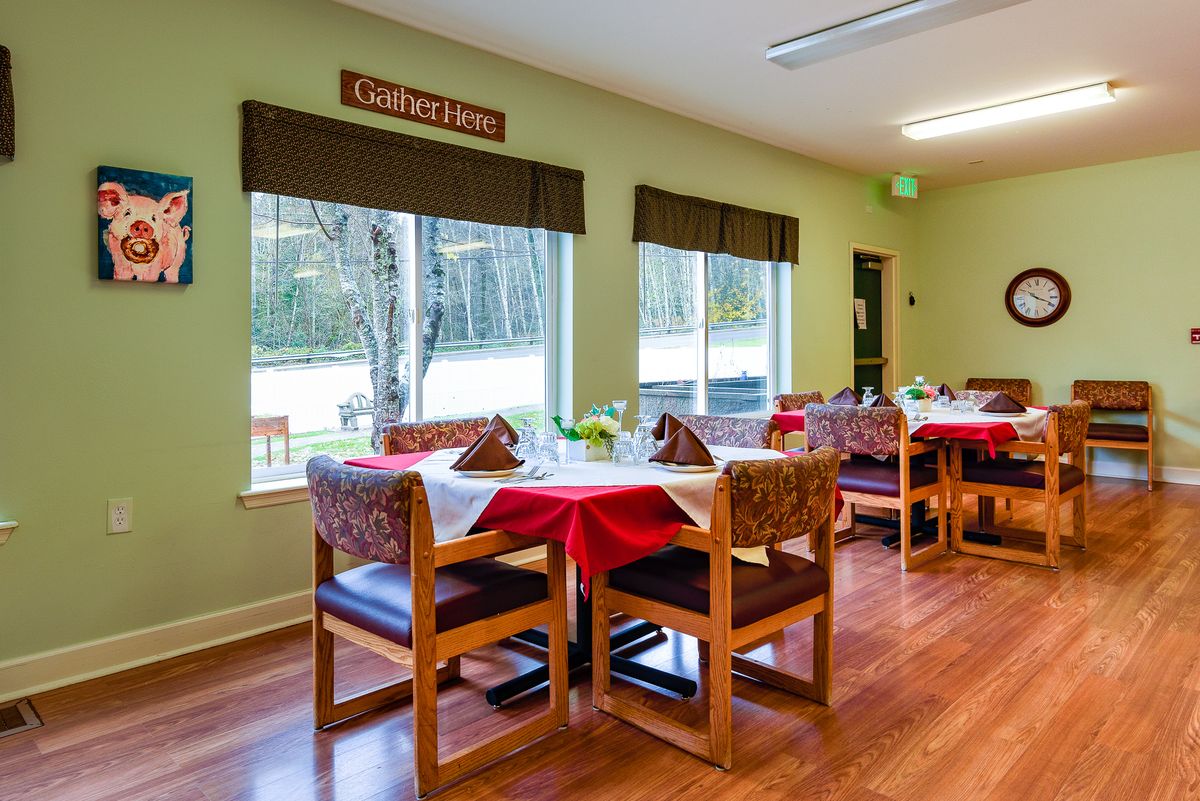 A cozy dining area with tables and chairs, set beside large windows with outside views.