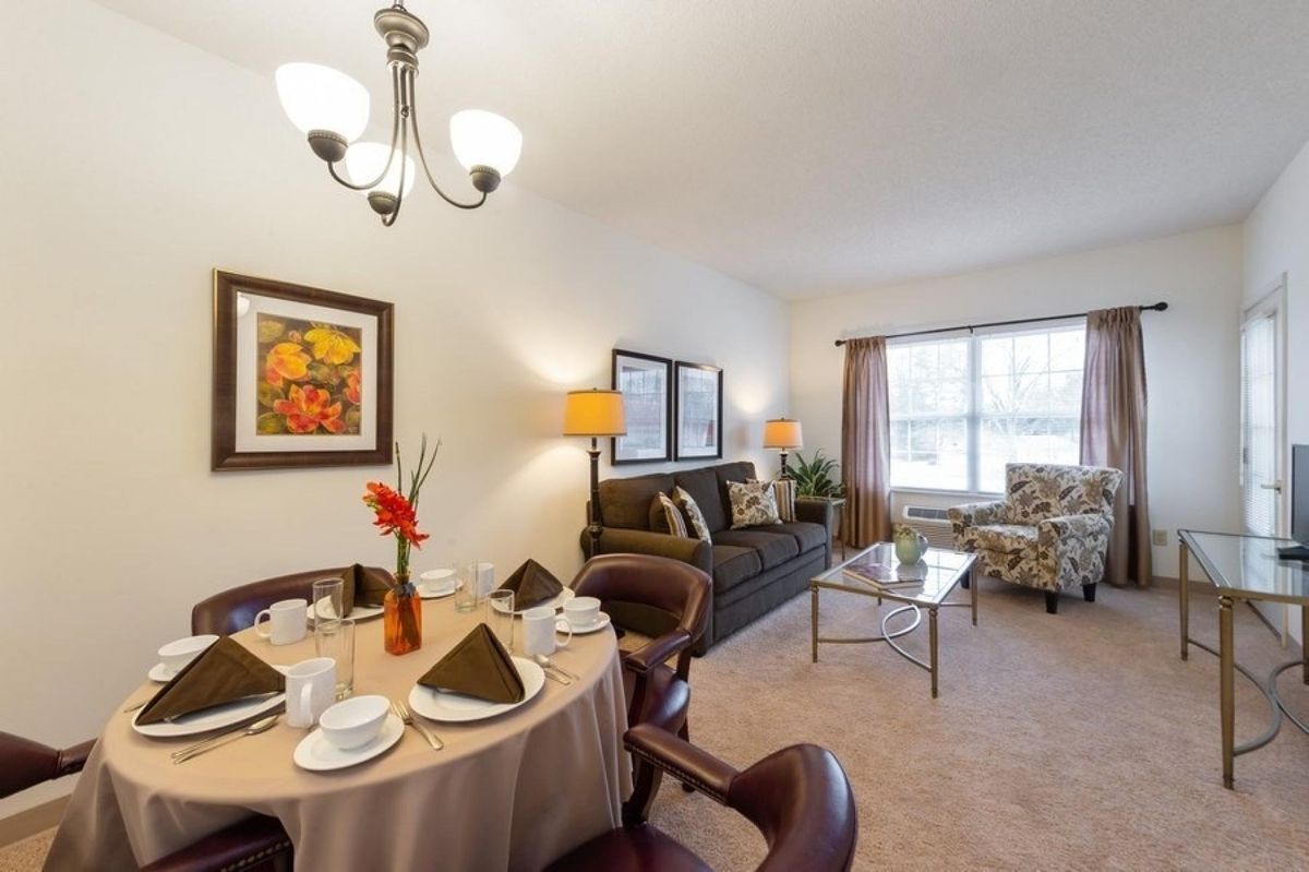 A cozy living and dining area with a neatly set dining table, comfortable sofa, and elegant decor.