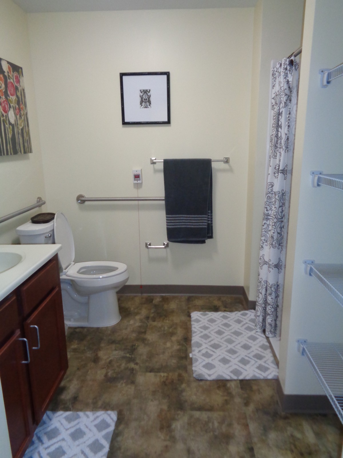 A modern bathroom with accessibility features, including handrails and a walk-in shower.