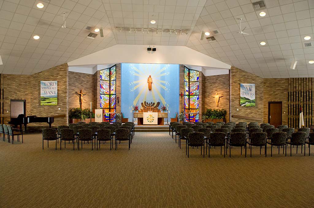 Interior view of a church with an altar and stained glass windows.