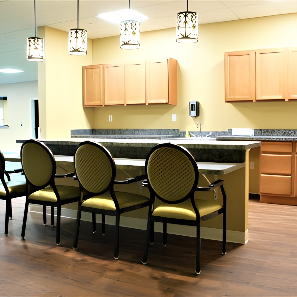 A modern kitchen interior featuring a countertop with chairs, wooden cabinets, and pendant lighting.