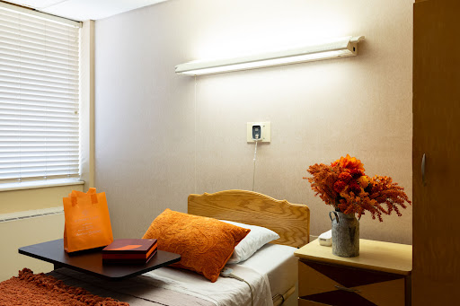 A cozy and well-lit bedroom featuring orange accents and floral decor.