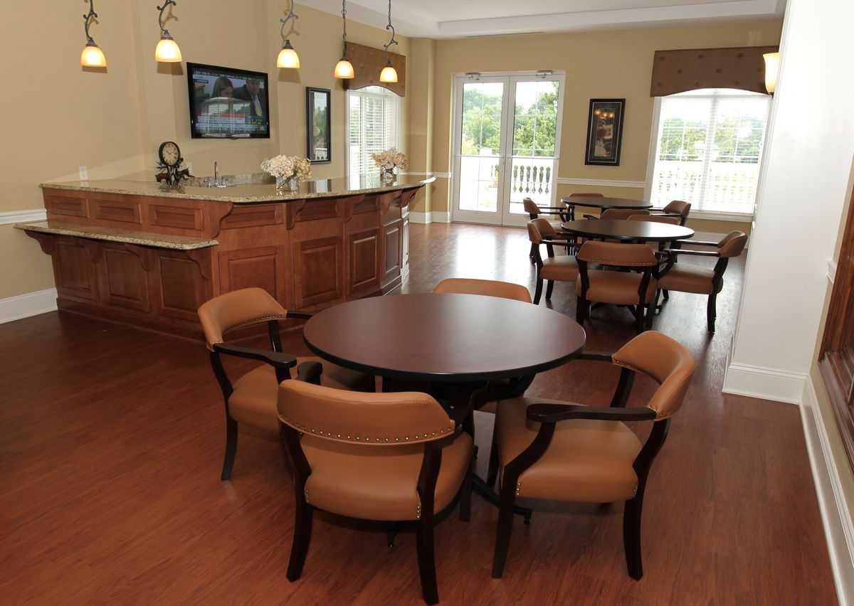 A modern dining area with a round table and cushioned chairs, featuring hardwood floors and pendant lighting.