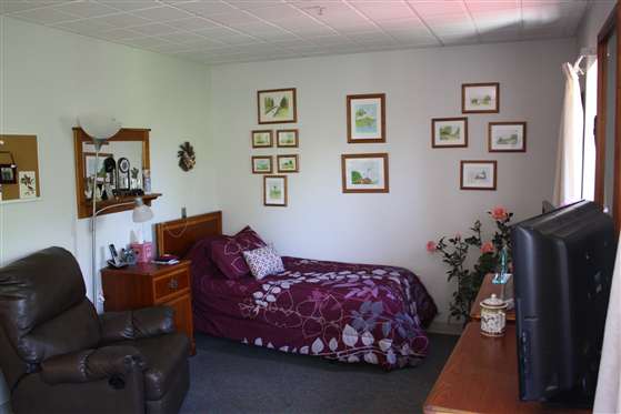 A cozy bedroom with purple-themed decor and wall art.