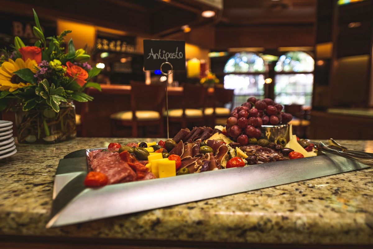 A gourmet charcuterie board featuring assorted cheeses, salami, and grapes in a cozy bar setting.