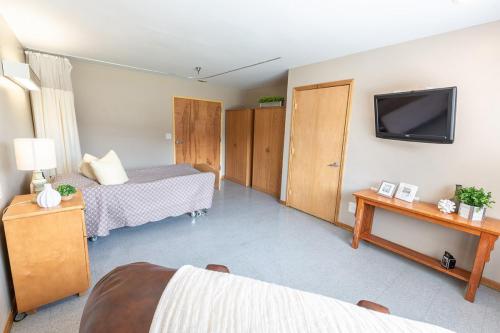 A cozy and minimalist bedroom featuring a bed, wooden doors, and a television.
