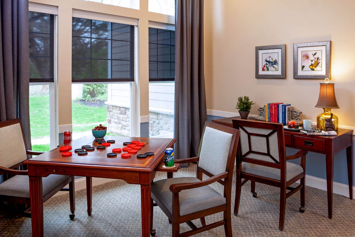 A cozy dining area with a wooden table set for breakfast, flanked by chairs and a window letting in natural light.
