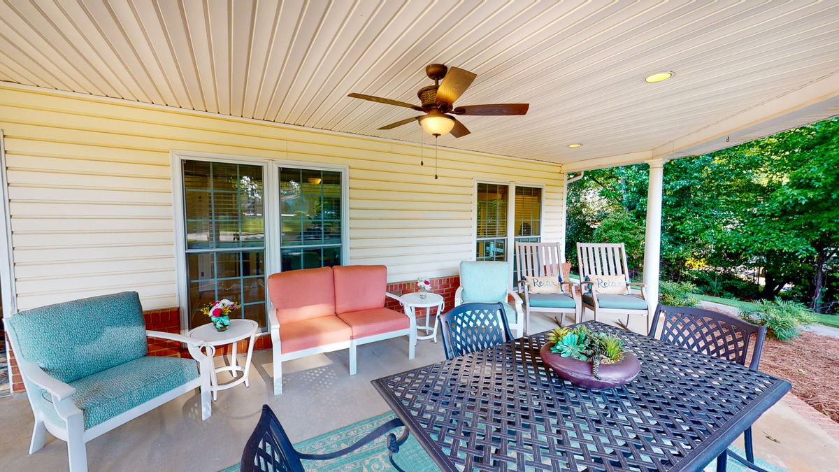 A cozy patio with comfortable seating and a ceiling fan, perfect for relaxing outdoors.