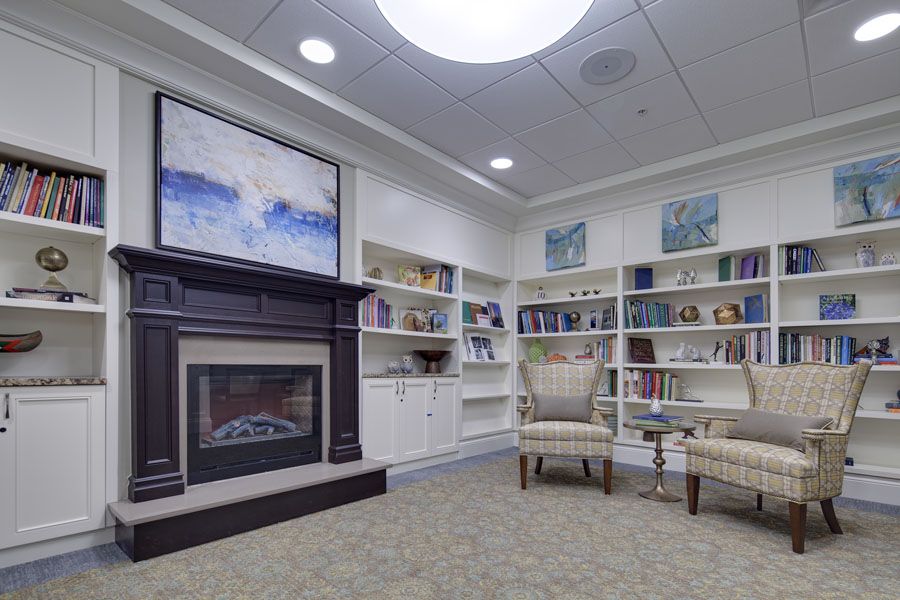 A cozy library corner with bookshelves, a fireplace, and comfortable seating.