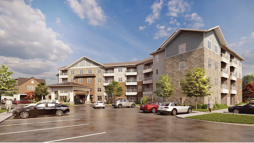 A modern apartment building featuring a spacious parking area and surrounded by greenery.