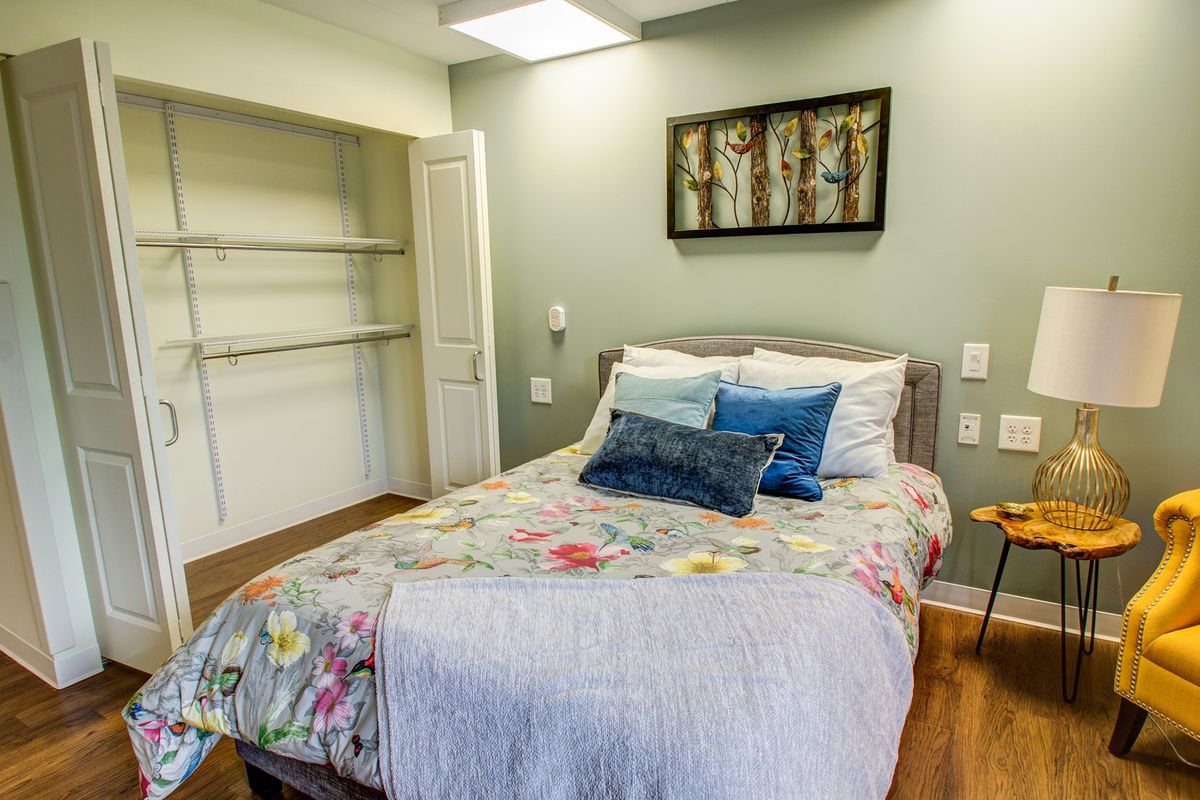 A cozy bedroom with a floral bedding set, decorative pillows, and an open closet.