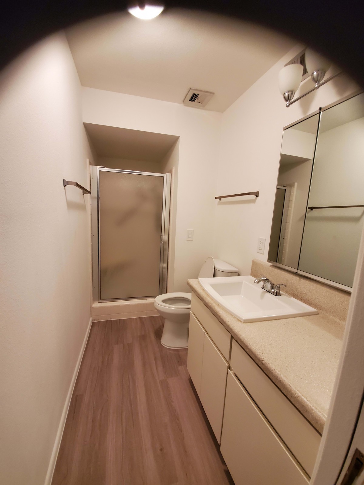 A small, modern bathroom featuring a shower, sink with a mirror, and a toilet.