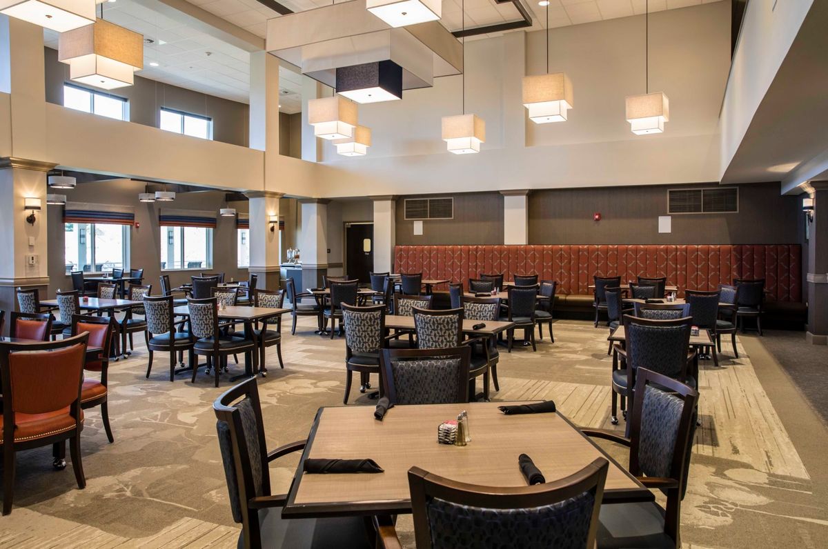 A modern restaurant interior featuring neatly arranged tables and chairs, with stylish lighting fixtures.
