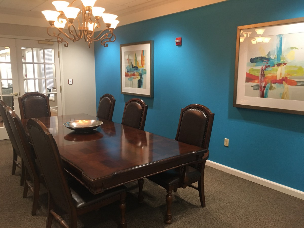 A cozy dining room featuring a wooden table, elegant chairs, and vibrant blue walls adorned with artwork.