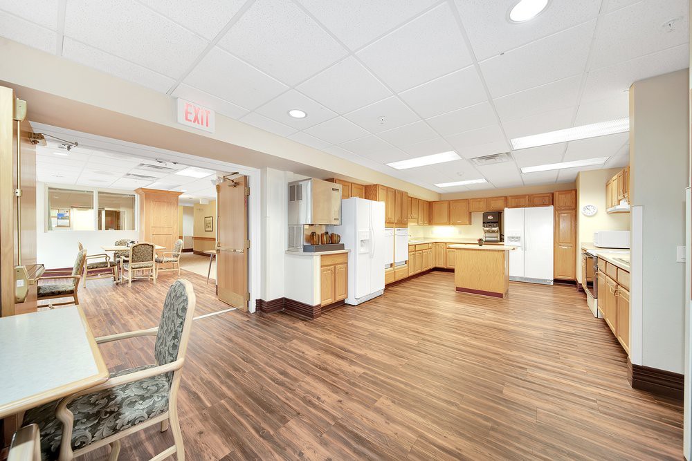 A spacious kitchen area featuring wooden floors, cabinets, and modern appliances.
