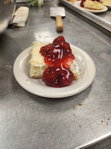 A slice of cheesecake topped with strawberry sauce served on a small plate.