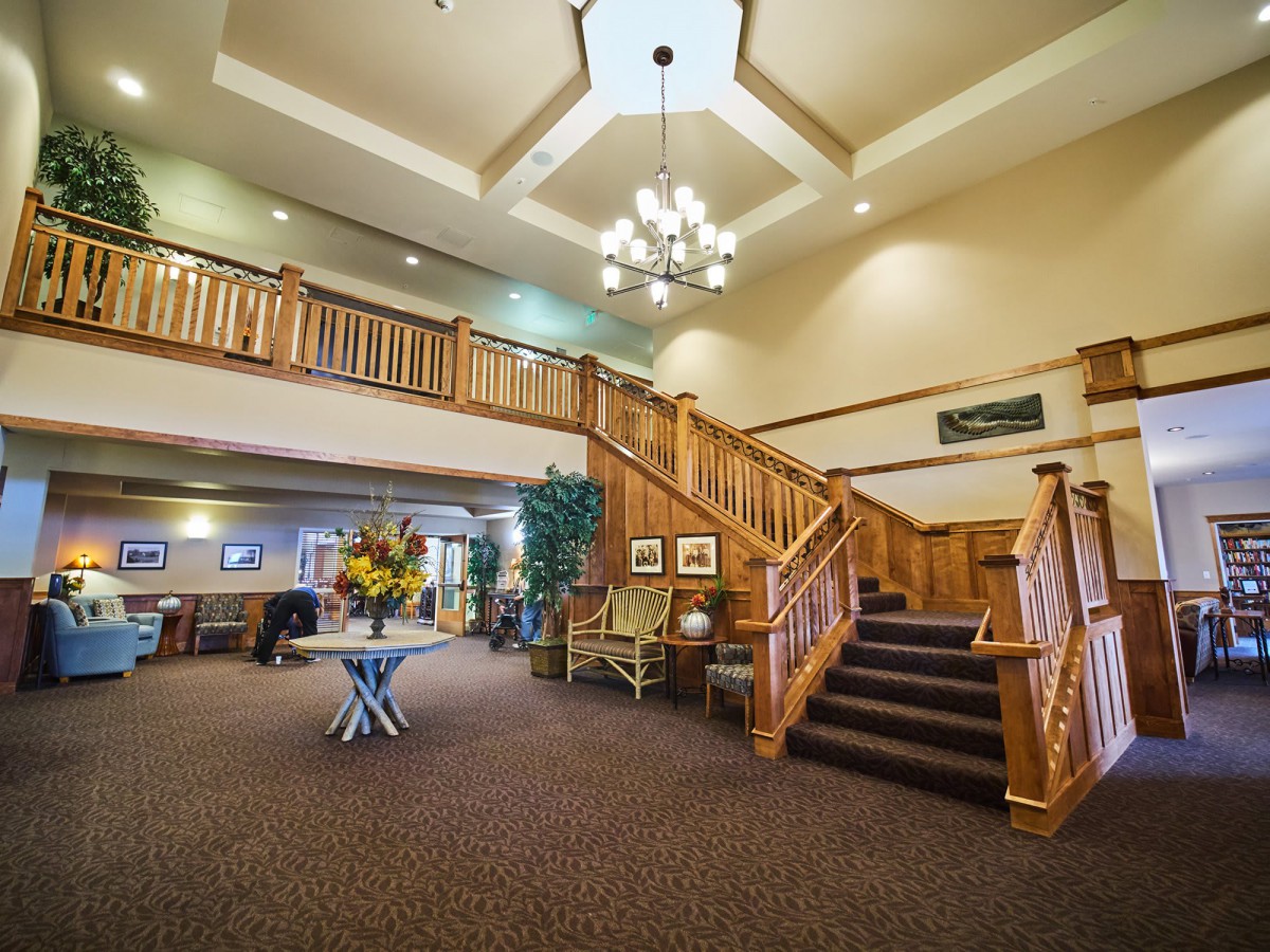 A spacious lobby with wooden stairs and a chandelier.