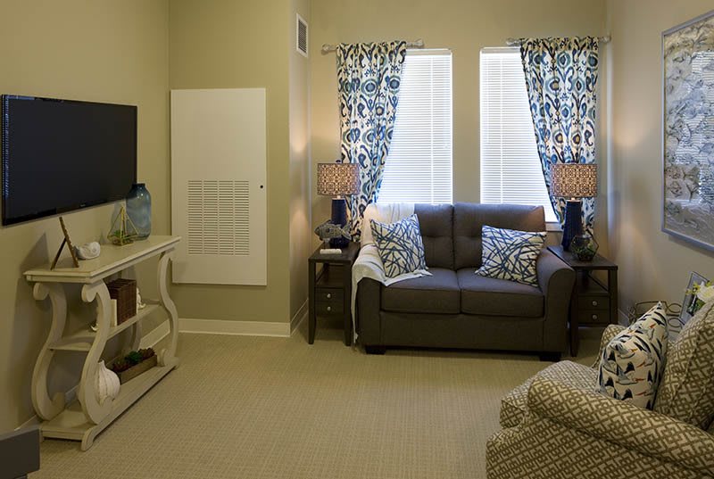 A cozy living room featuring a couch, television, and stylish curtains.
