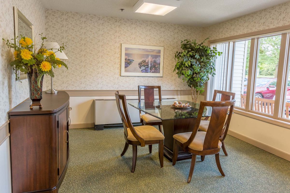 A cozy dining room with a glass table, chairs, and decorative elements like plants and artwork.