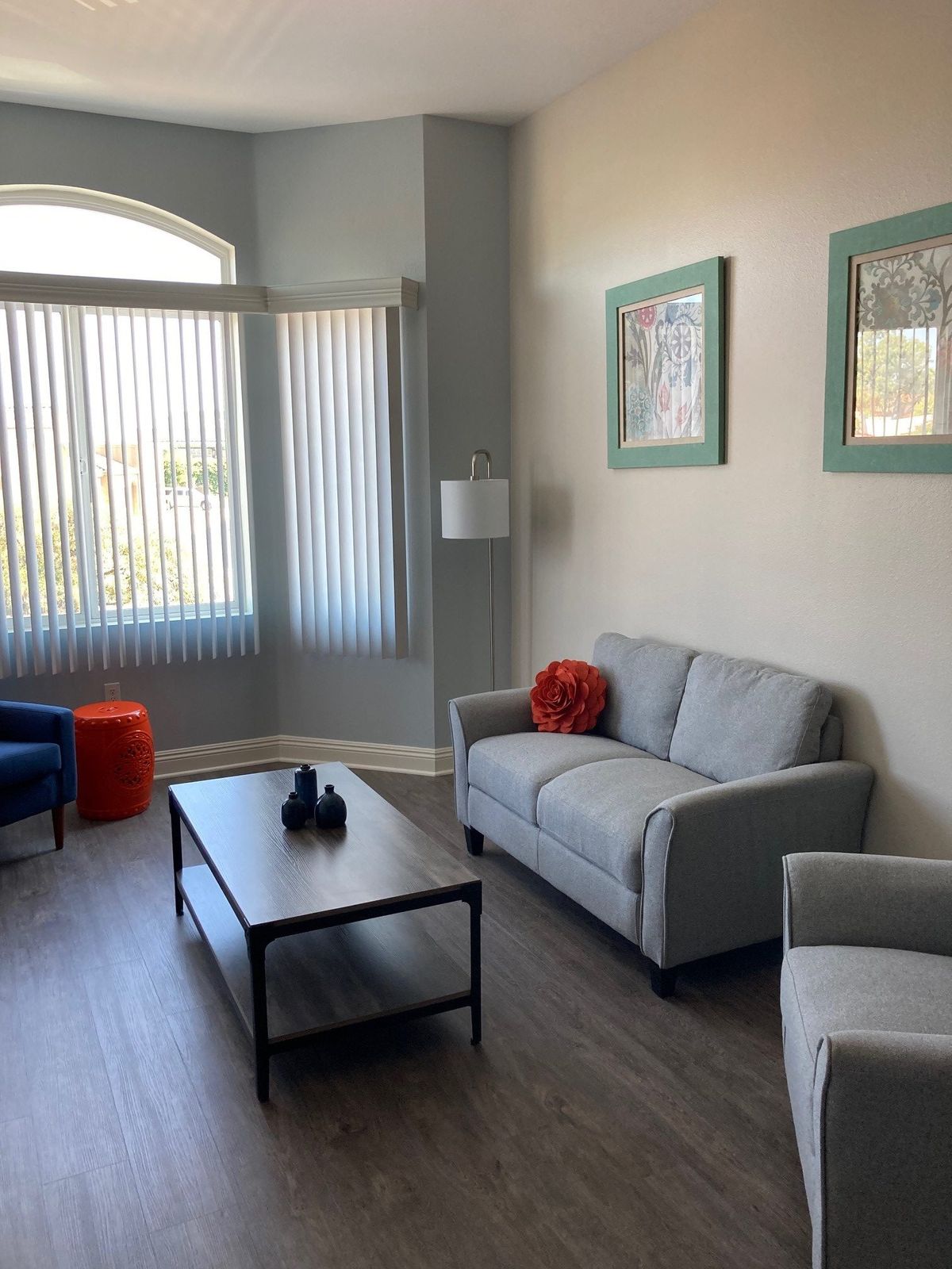 A cozy living room with a sofa, armchair, coffee table, and artwork on the walls.