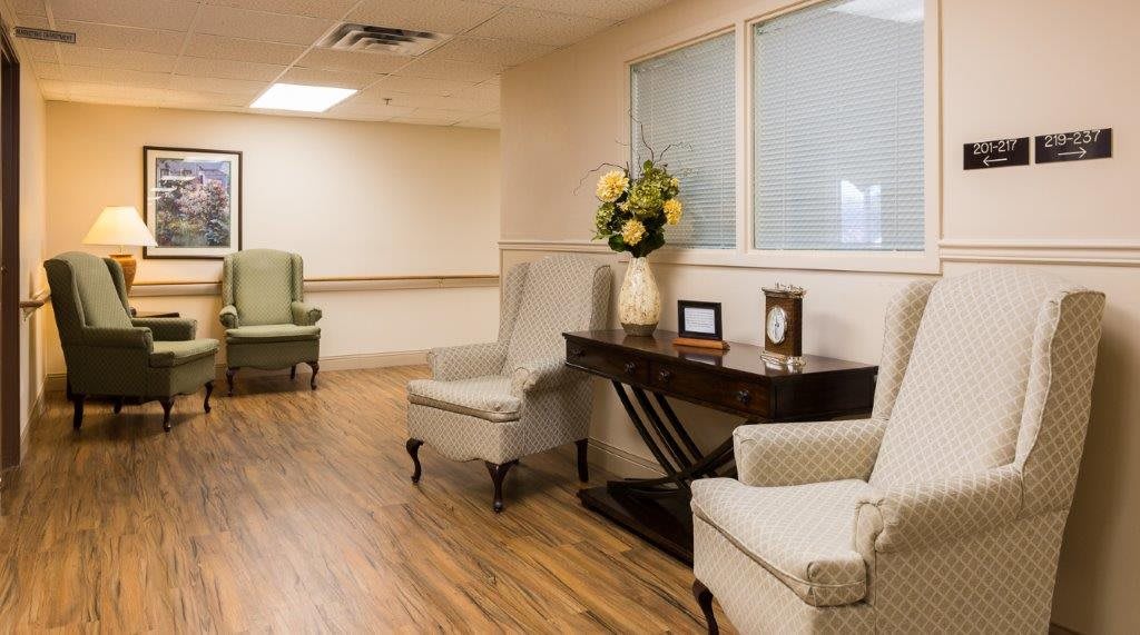 A serene waiting room with comfortable chairs, a wooden table adorned with flowers, and a small clock.