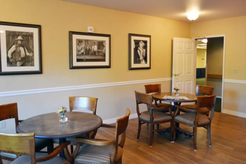 A cozy cafe interior with wooden tables and chairs, decorated with framed artwork on the walls.