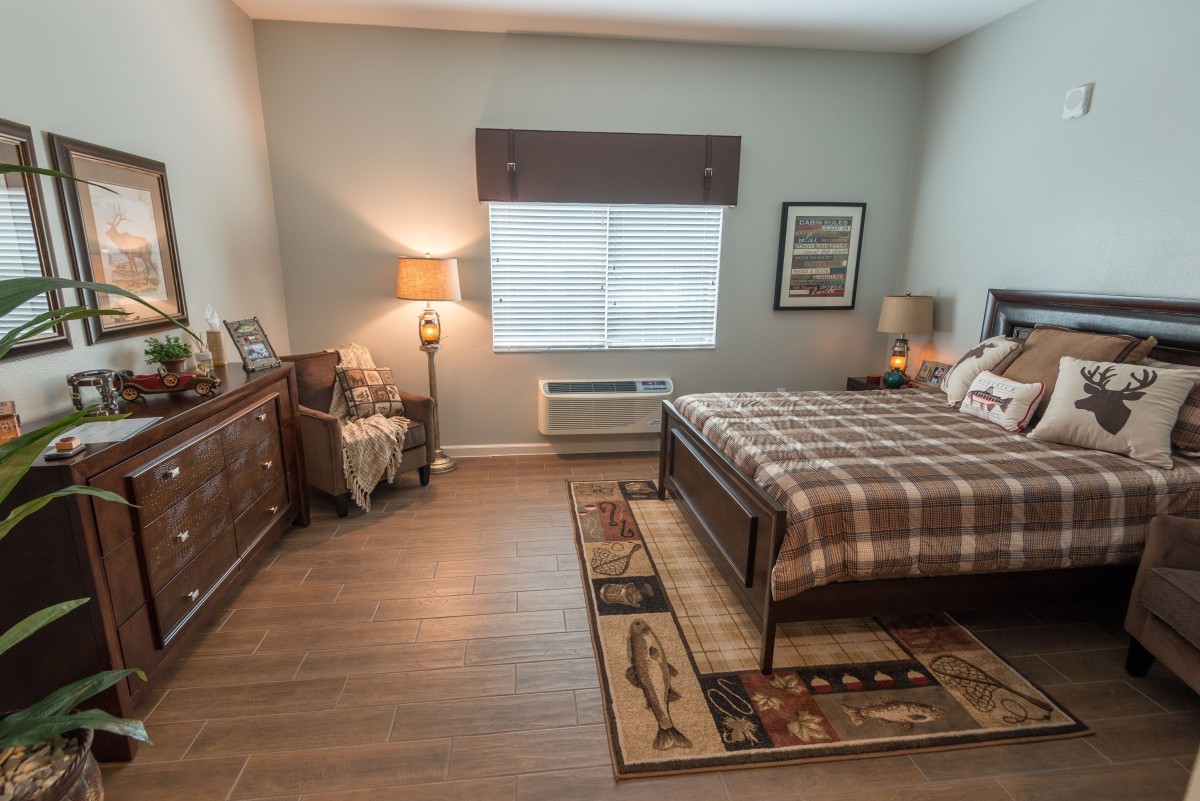 A cozy bedroom with a checkered bedspread, wooden furniture, and warm lighting.