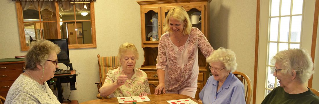 A caregiver assists elderly individuals in playing a game together indoors.