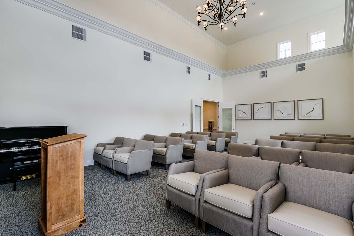 A well-furnished waiting room or conference area with multiple chairs and a chandelier.