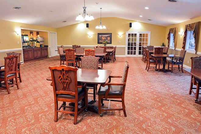 A spacious dining room with tables and chairs arranged neatly on a carpeted floor.