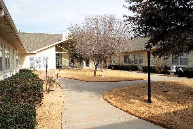 A view of a building with a pathway and trees in the foreground.