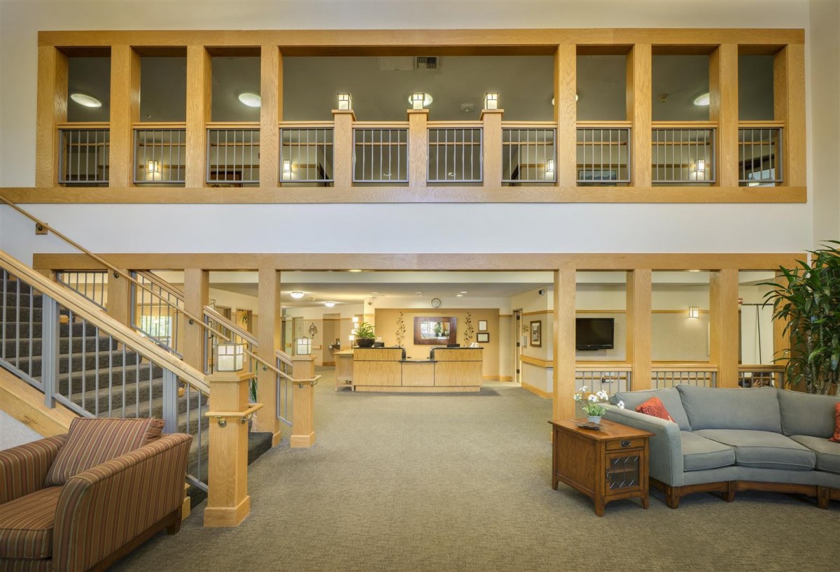 A spacious lobby area featuring a reception desk, wooden railings, and comfortable seating.