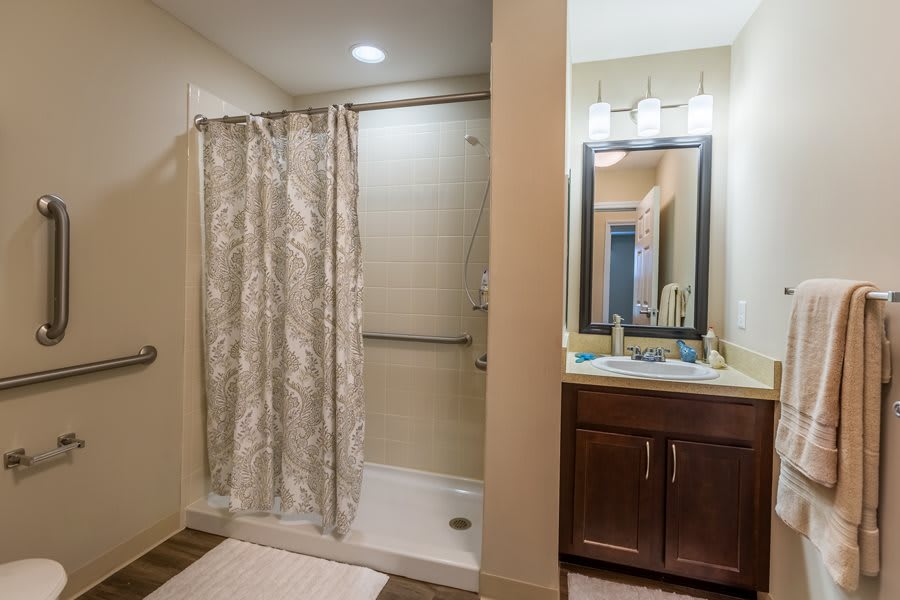 A modern bathroom with a shower curtain, vanity sink, and mirror.