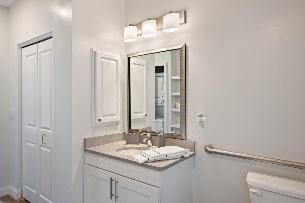 A modern bathroom featuring a sleek vanity with a large mirror and an overhead light fixture.