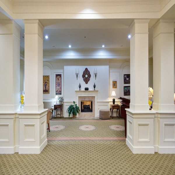 A luxurious hotel lobby featuring elegant columns, a central fireplace, and comfortable seating areas.