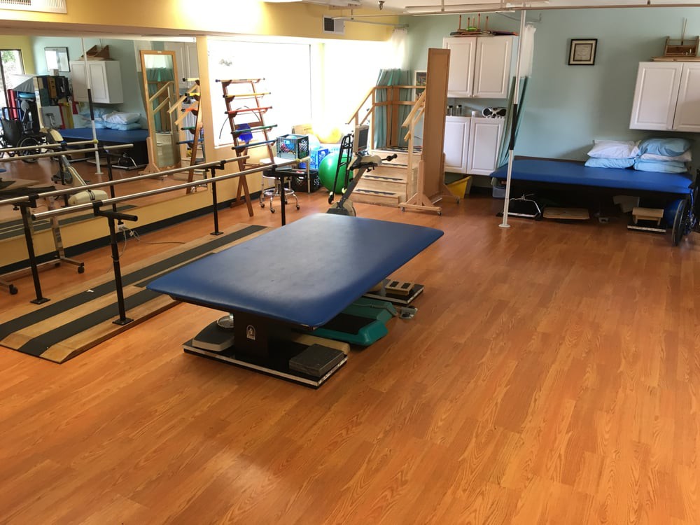 A spacious physical therapy room featuring a treatment table and various exercise equipment.