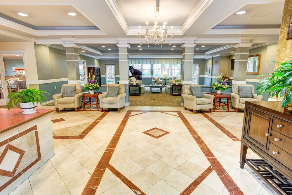 A spacious and elegantly designed lobby with comfortable seating, a piano, and a chandelier.