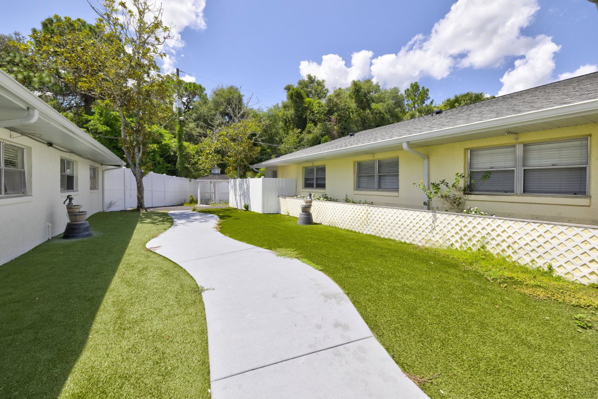 A serene backyard garden with a winding sidewalk and well-maintained lawn.