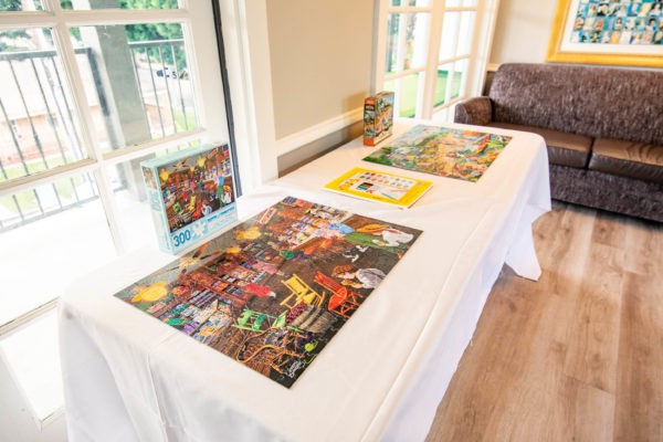 A table displaying completed jigsaw puzzles in a bright interior space.