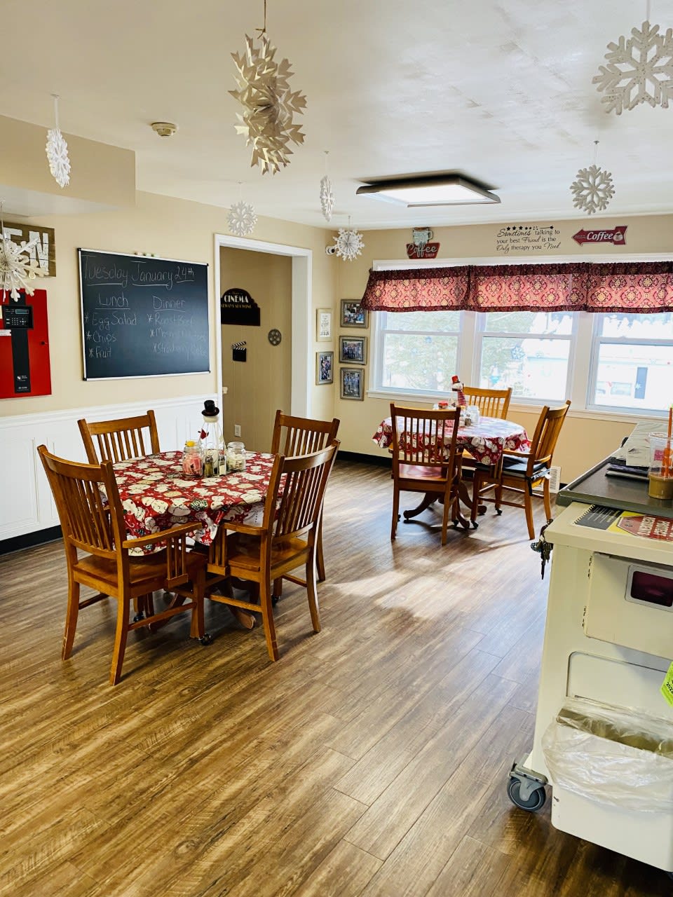 A cozy dining area with wooden tables and chairs, adorned with festive decorations.