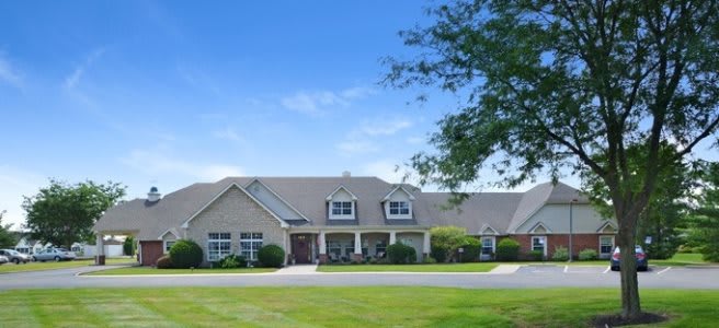 A large suburban house with a well-maintained front yard under a clear blue sky.