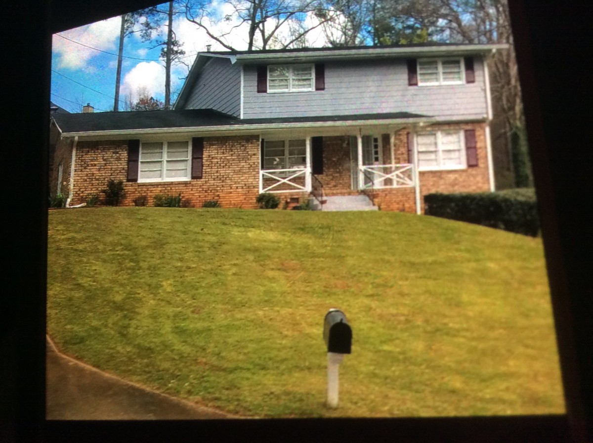 A suburban two-story house with a brick exterior and well-maintained lawn.