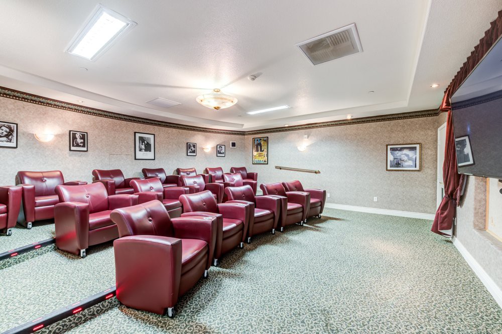 A cozy home theater with rows of plush red chairs.