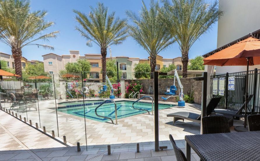 A tranquil outdoor swimming pool surrounded by palm trees in a residential area.