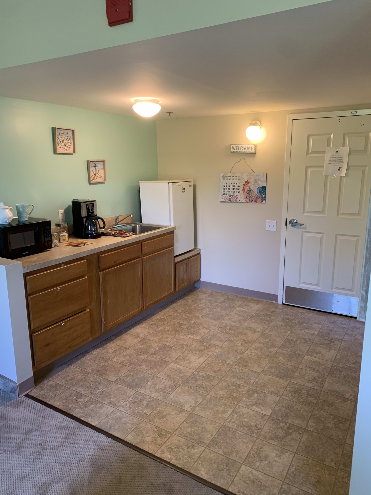 A compact kitchen setup with essential appliances, including a microwave, coffee maker, refrigerator, and sink.
