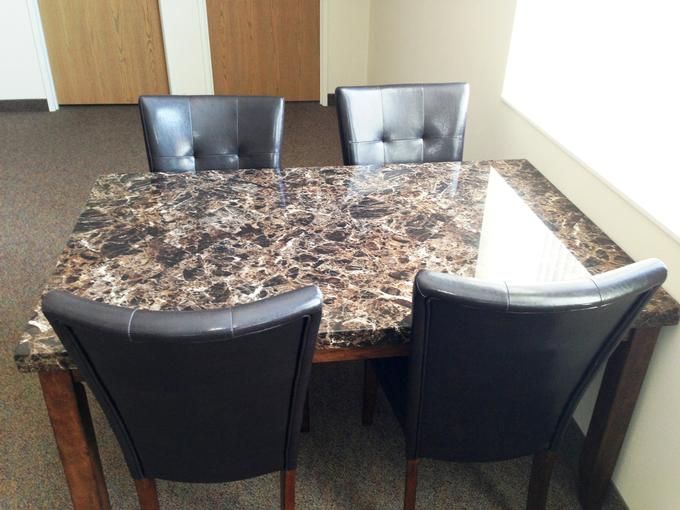 A marble-top dining table with four black chairs.