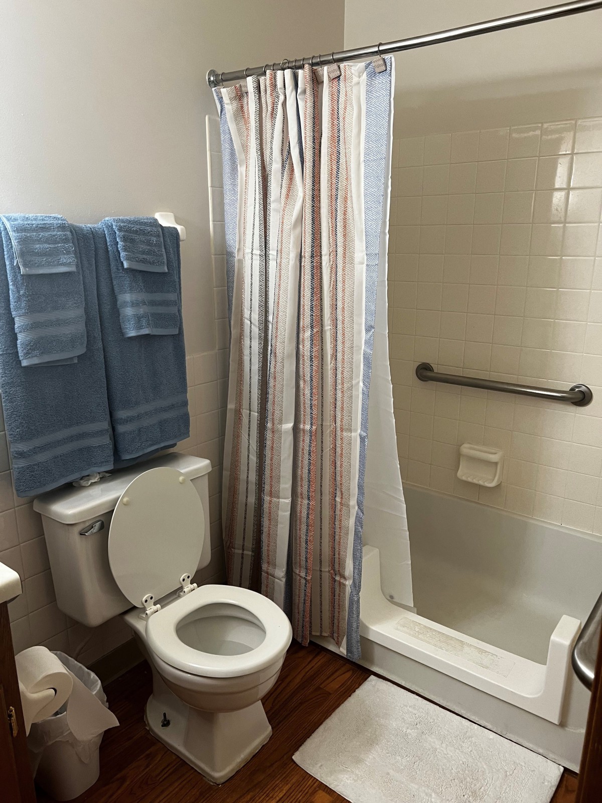 A clean bathroom with a shower, toilet, and neatly hung blue towels.