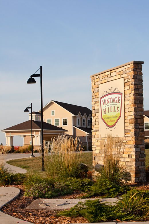 Entrance to a vineyard and winery with a sign and nearby building.